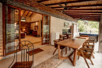 A luxurious eco-villa at Arsulana Lodge, featuring stone walls and large windows that open onto the lush greenery of the Ginigathena jungle.