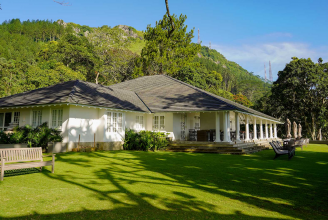 The grand colonial facade of W15 Hanthana Estate, surrounded by rolling green tea hills and misty mountains in Kandy.