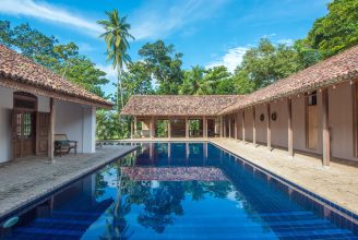 The elegant white facade of Maya Tangalle, a traditional Sri Lankan manor house surrounded by lush tropical gardens and a shimmering swimming pool.