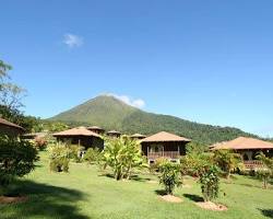 Wooden bungalows at Lomas del Volcán accommodation with a direct view of Arenal Volcano in La Fortuna, Costa Rica.