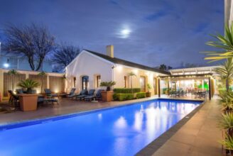 The swimming pool at The Portswood Hotel at night, with the hotel building illuminated in the background at the V&A Waterfront, Cape Town.